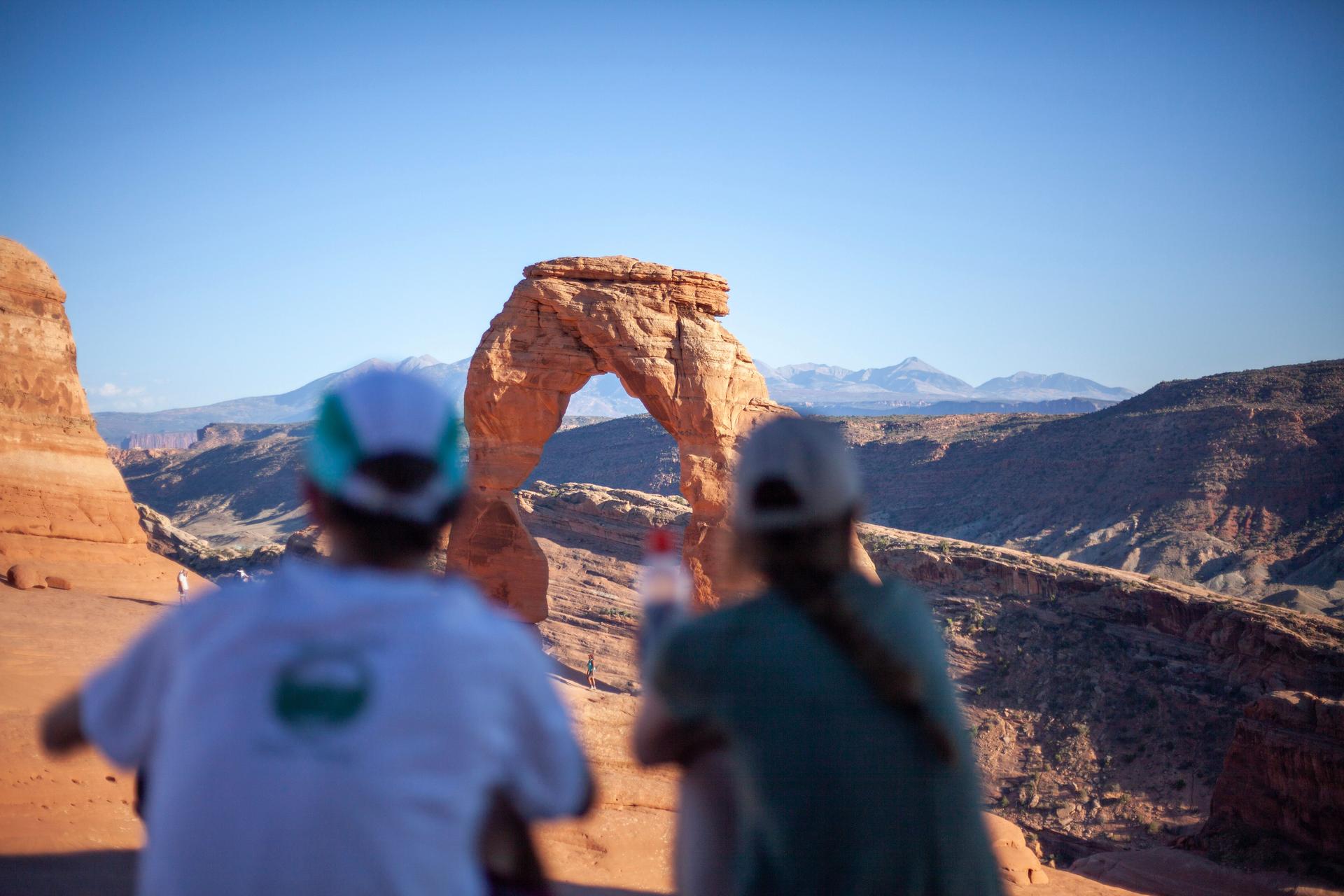 Couple look at natural arch in canyon lands, Utah